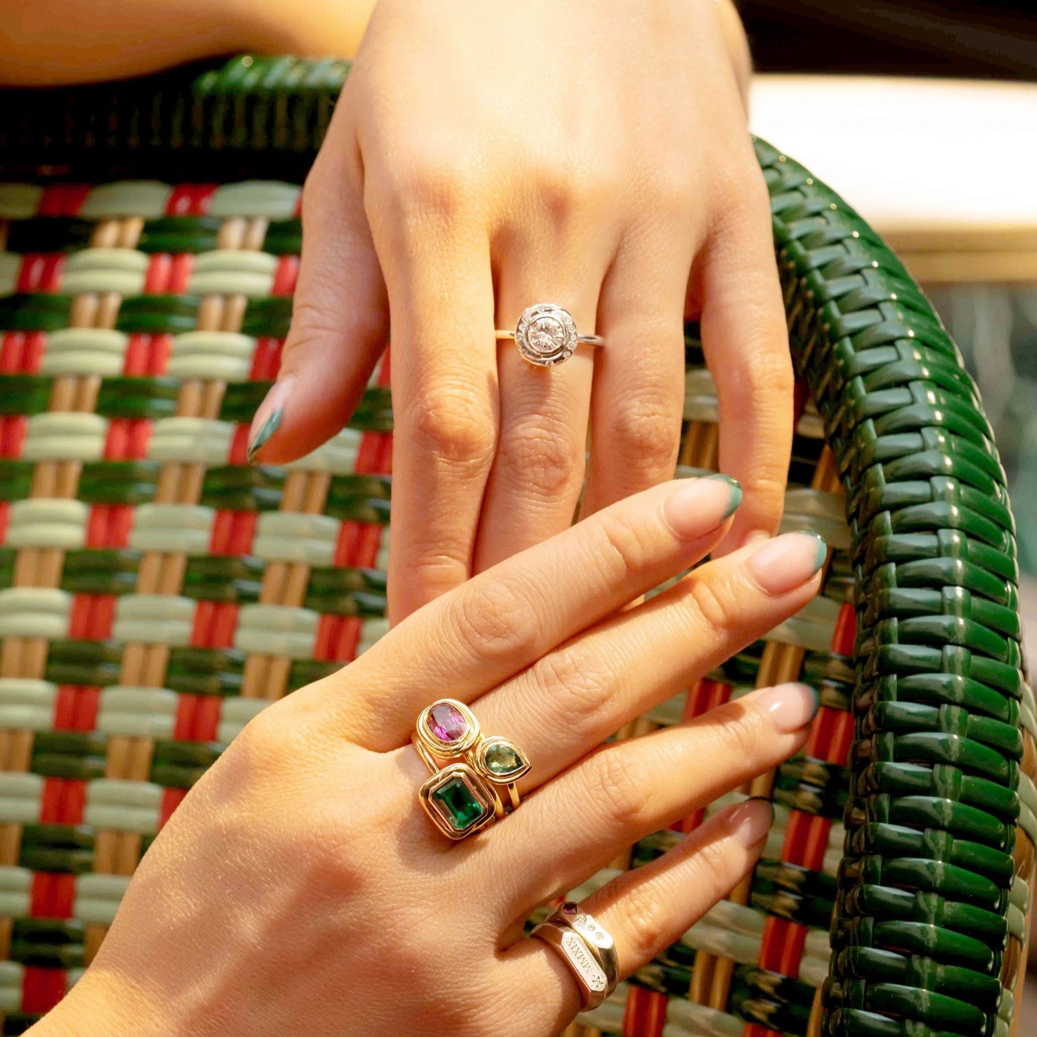 Close-up of hands wearing stacked rings with a woven chair background