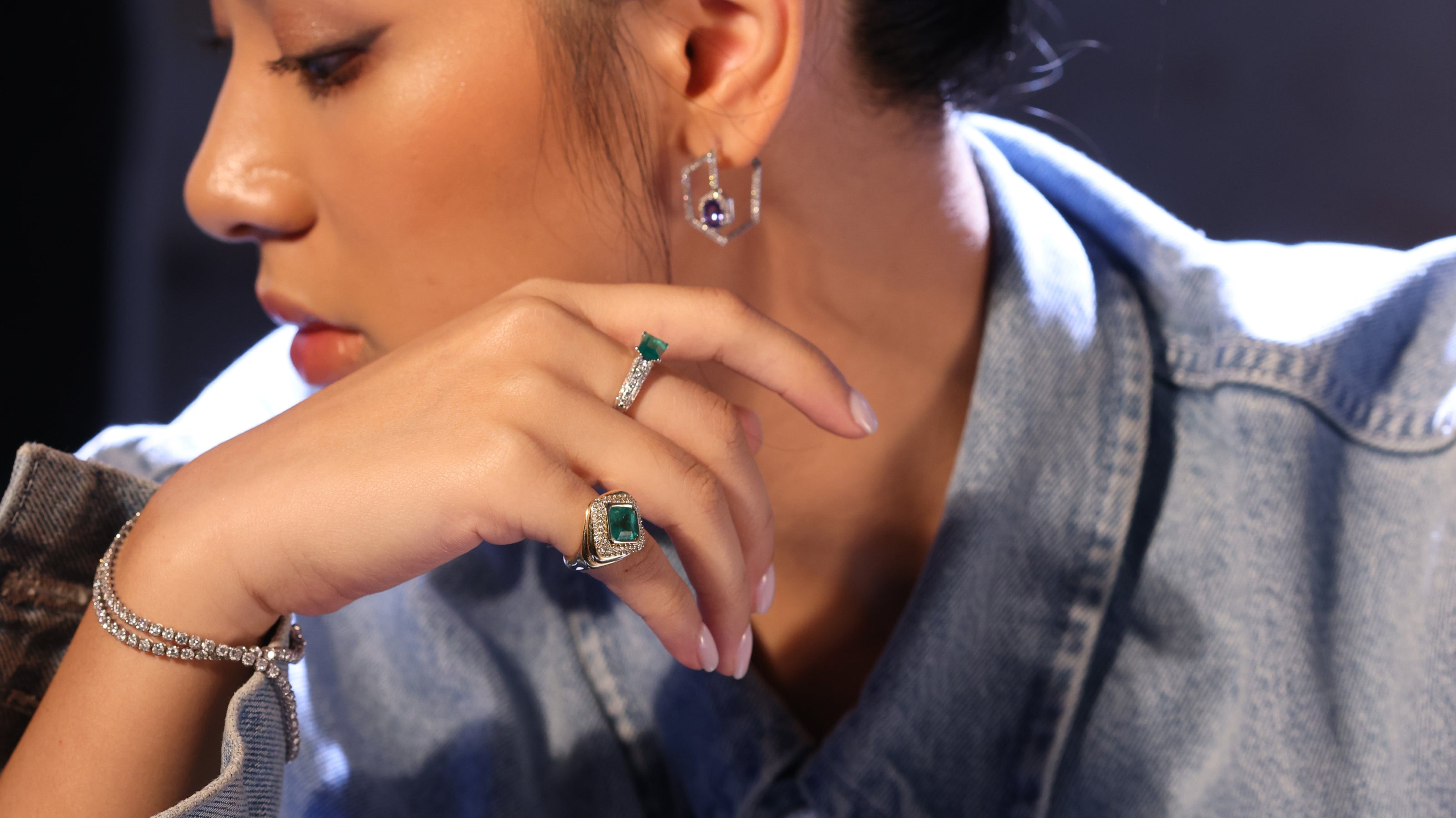 Close-up of Kjx model wearing emerald rings and Kore hoop Tanzanite earring